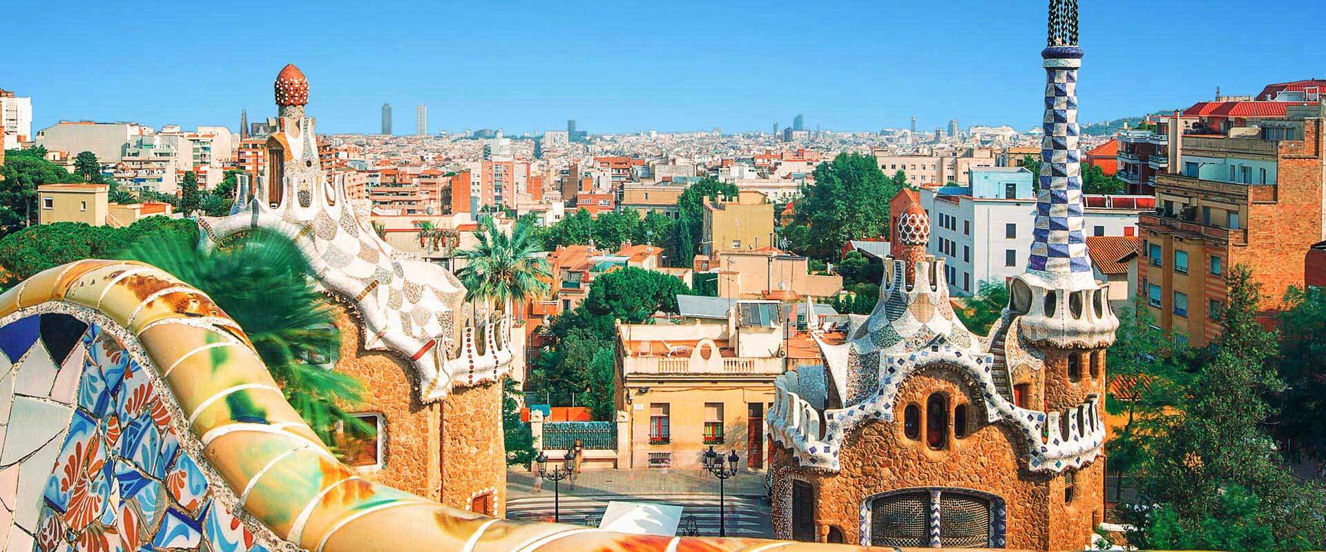 Panoramablick auf den Park Güell in Barcelona mit den bunten Gaudí-Strukturen und der Stadt im Hintergrund.